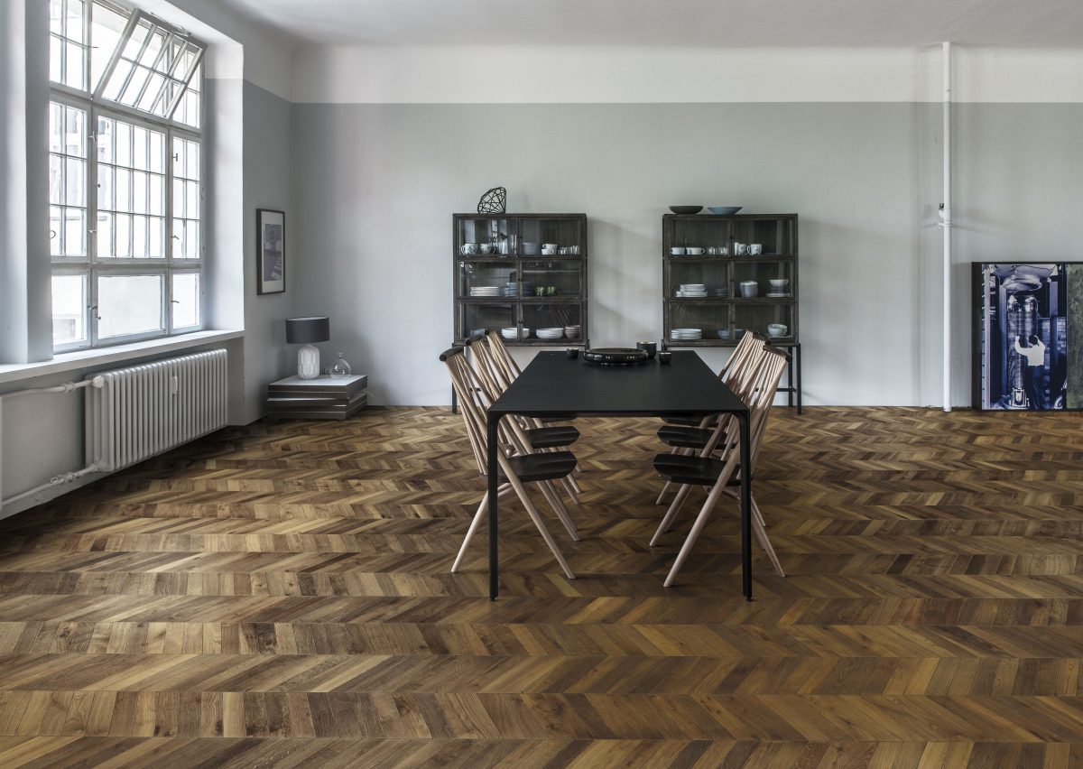 Decorated dining space with Kahrs Chevron Dark Brown Prefinished Hardwood.