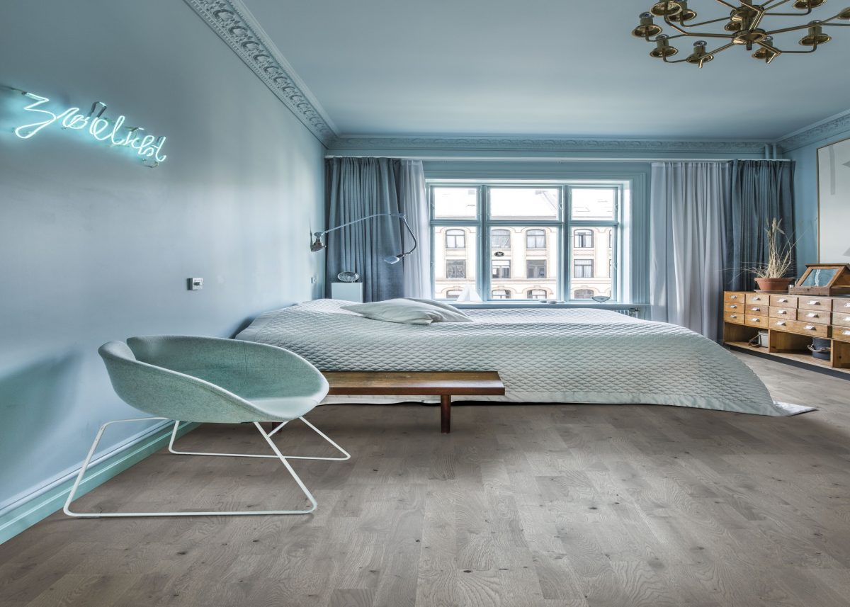 Decorated bedroom space with Kahrs Pearl Grey Strip Prefinished Hardwood.